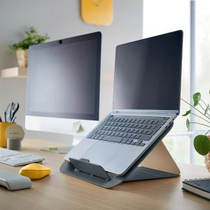 szara podstawka z laptopem, postawiona na biurku obok monitora komputerowego