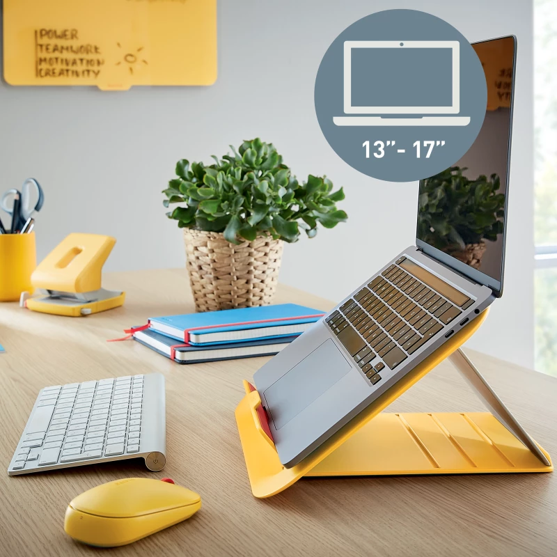  żółta podstawka z laptopem, postawiona na biurku z myszką i klawiaturą